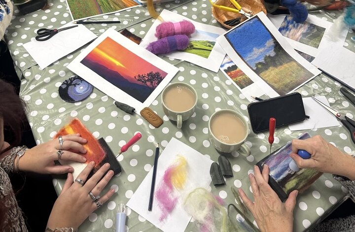 hands working on felt landscape craft activity, cup of tea in frame