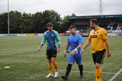 3 football players walking on a football pitch