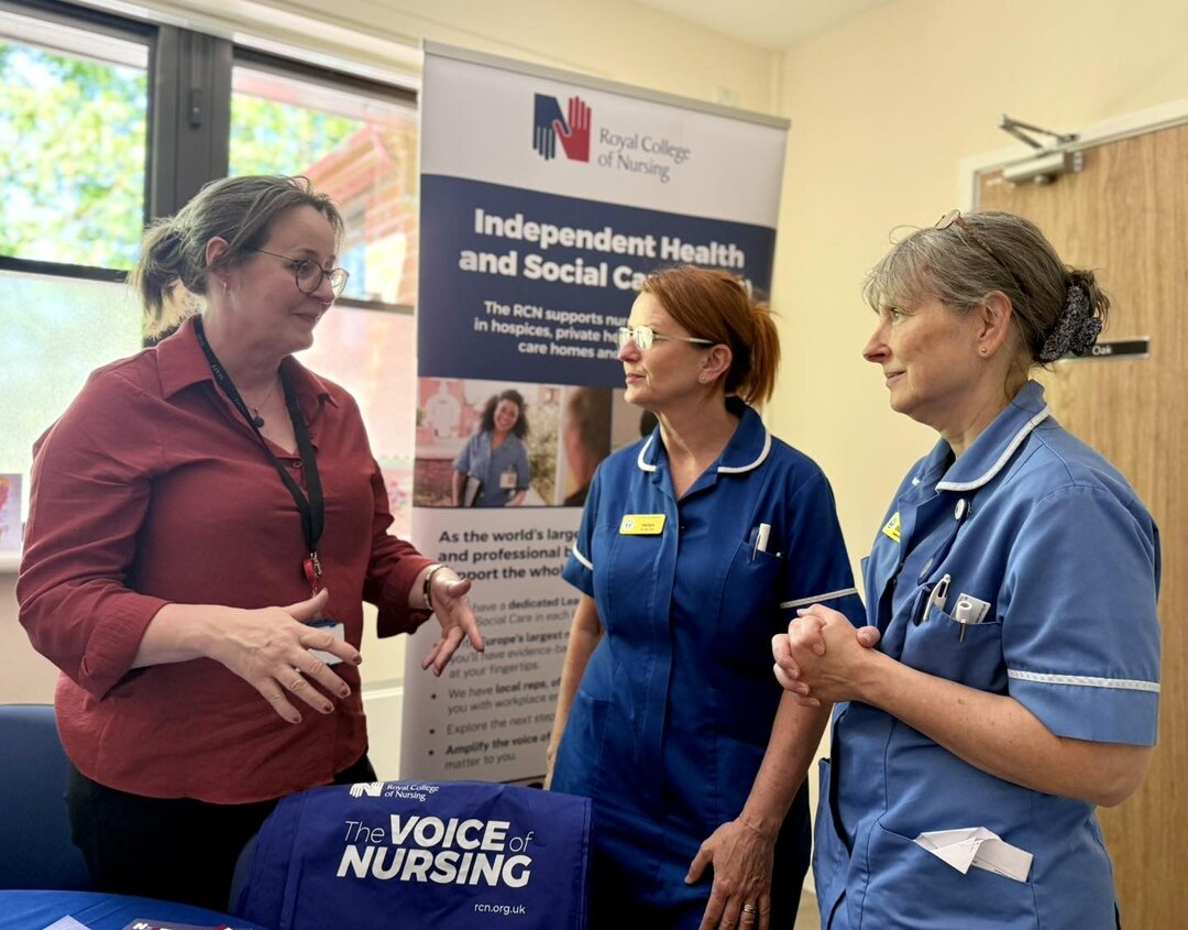 A woman talking to two nurses with a pull up banner in the background