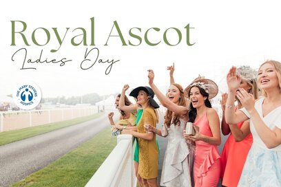 Text: happy, well-dressed women at the side of a horse racing track cheering and having a lovely time